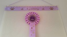 a pink award ribbon hanging from a wall with paw prints on it and the words agility 4