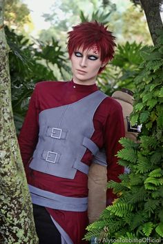 a man with red hair and blue eyes is standing in the woods wearing a costume