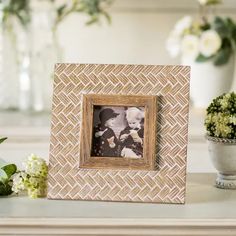 a small wooden frame with a photo in it on a table next to some flowers