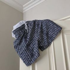 a blue and white shorts hanging on the wall next to a door with an open pocket