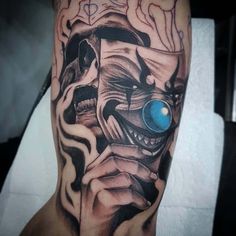 a man's leg with an evil clown tattoo on it and a blue eye