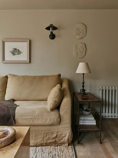 a living room with a couch, lamp and pictures on the wall above it's radiator