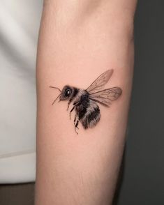 a small bee tattoo on the arm