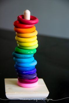 a stack of colorful rings sitting on top of a wooden table next to a candle