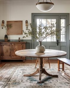 a dining room table with a vase on it and two benches in front of the door