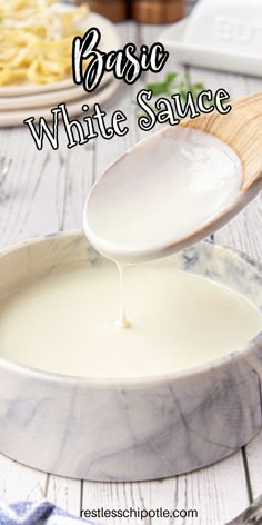 white sauce being poured into a bowl on a table with pasta and cheese in the background