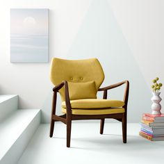 a yellow chair sitting on top of a white floor next to a stack of books