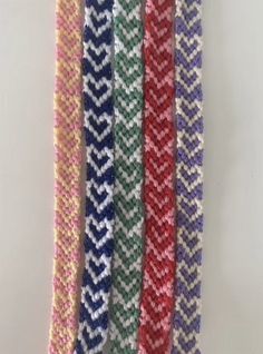 five different colored chevroned knitted ties hanging from a hook on a wall