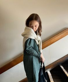 a woman standing in front of a piano wearing a scarf over her head and looking down