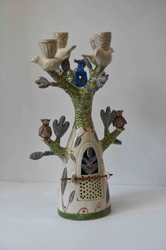 a ceramic tree with birds perched on it's branches and a birdhouse in the middle