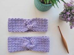 two crocheted headbands sitting on top of a table next to a potted plant