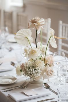 the table is set with white flowers and silverware