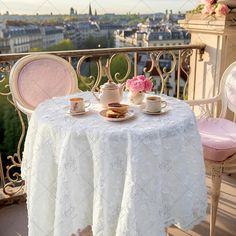 a table with two tea cups and plates on top of it, overlooking the city