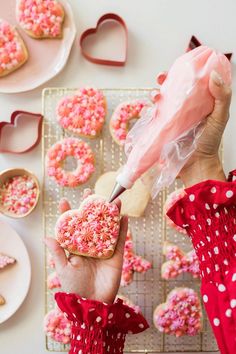 a person is decorating some cookies with pink sprinkles and icing