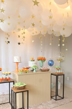 the dessert table is set up with balloons and stars hanging from the ceiling above it