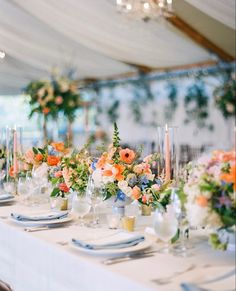 the table is set with white linens and colorful floral centerpieces on each place setting