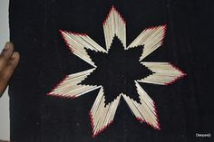 an image of a star made out of matchesticks on a black cloth with red and white lines