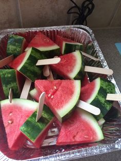 slices of watermelon and toothpicks on sticks in a tin foil container