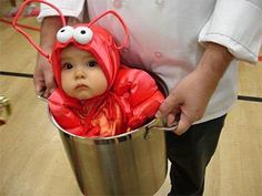 a man holding a bucket with a baby dressed as a bug in it's mouth