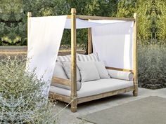 an outdoor day bed with white drapes on it's sides and pillows on the bottom