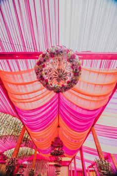 the inside of a pink and orange tent with flowers on it's ceiling is covered in sheer fabric