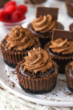 chocolate cupcakes with frosting and strawberries in the background on a white plate