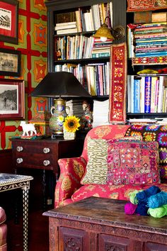 a living room filled with lots of furniture and bookshelves covered in colorful fabrics