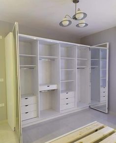 an empty room with white closets and drawers on the floor, in front of a chandelier