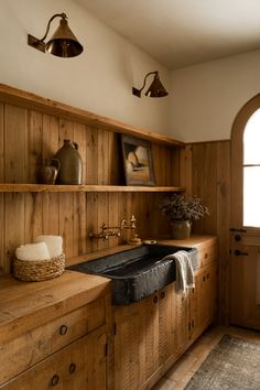 a kitchen with wood paneling and open shelving on the wall next to a sink