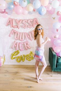 a woman standing in front of balloons and streamers with the words always young yet on it