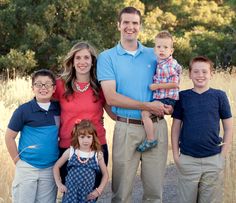 a family poses for a photo in front of some tall grass and trees at sunset