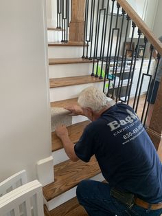 a man kneeling down to pick up carpet from the stairs in a house that has been painted white