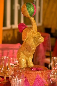 a table topped with a cake covered in pink and gold frosting next to wine glasses