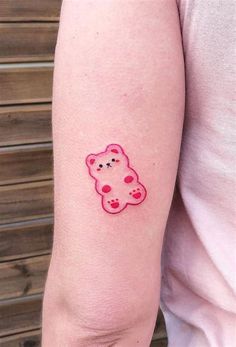 a small pink teddy bear tattoo on the left arm