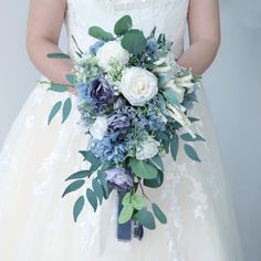 a woman in a wedding dress holding a bridal bouquet with blue and white flowers