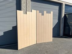 two tall wooden gates sitting next to each other in front of a garage door with shutters