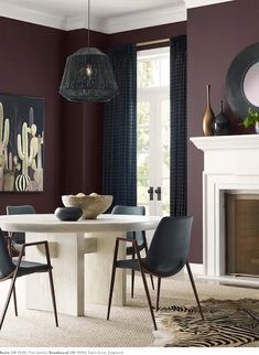 a dining room with purple walls and white table surrounded by chairs in front of a fireplace