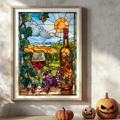 a stained glass window with wine bottles and grapes on it next to two pumpkins