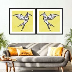 two framed art prints on the wall of a living room with couches and coffee table