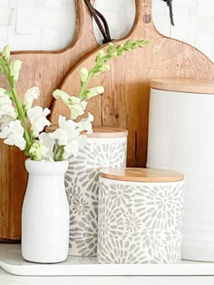 three vases with flowers in them sitting on a shelf next to a wooden clock