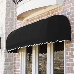 a black awning on the side of a brick building with white trim and windows