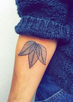 a woman's arm with a tattoo on it that has an image of a leaf