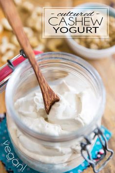 a jar filled with yogurt sitting on top of a wooden table next to a spoon