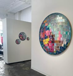 two colorful mosaic tiles on the wall next to each other in an art gallery with white walls and black flooring