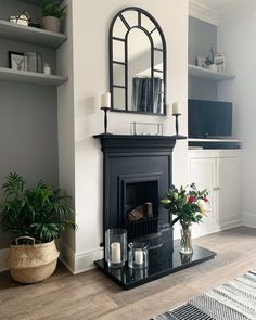 a living room with a fireplace, mirror and potted plants