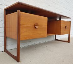 a wooden desk with two drawers on the bottom and one drawer open to reveal something