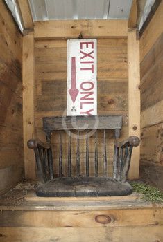 an exit only sign in the corner of a wooden room with a bench and chair