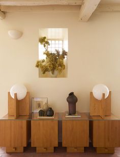 two vases on top of wooden cabinets in a room with white walls and red tile flooring