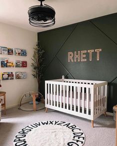 a baby's room decorated in green and white with a crib next to the wall