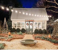 a small white house with christmas lights on the front door and windows in the back yard